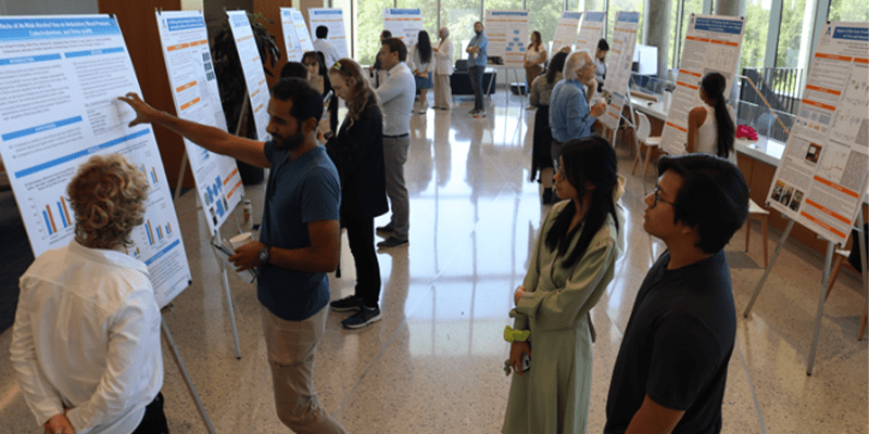 Student presenting his research poster in font of a crowd